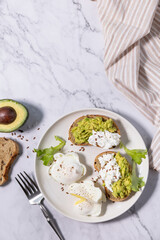 Easter breakfast or brunch. Delicious breakfast or snack - poached egg and cream cheese toast whole grain rye bread, avocado on a marble tabletop. Top view flat lay. Copy space.