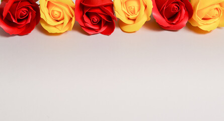 yellow and red roses on a pale pink background, free space for text, elegant spring composition, flower frame