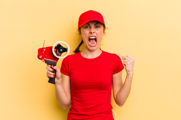 young pretty woman shouting aggressively with an angry expression. packer concept