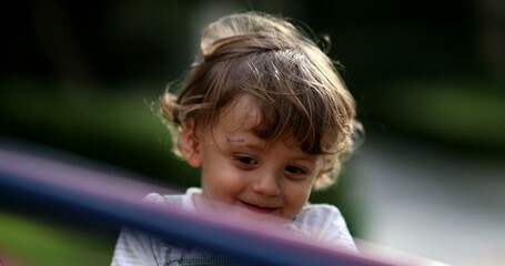 Carefree little boy spinning at playground carousel close-up face smiling