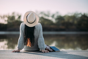 Unrecognizable young woman with hat enjoying nature on the bank of a river - Powered by Adobe