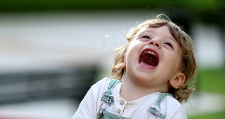 Carefree little boy spinning at playground carousel close-up face smiling