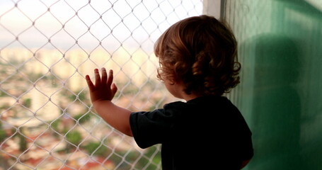 Baby child hand leaning on window balcony with safety net