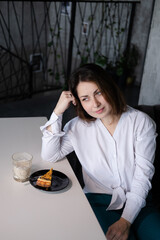 woman in white blouse in a cafe with a cup of coffee and dessert. coffee break. business woman.