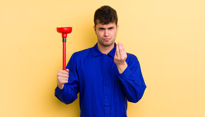 young handsome man making capice or money gesture, telling you to pay. plumber concept