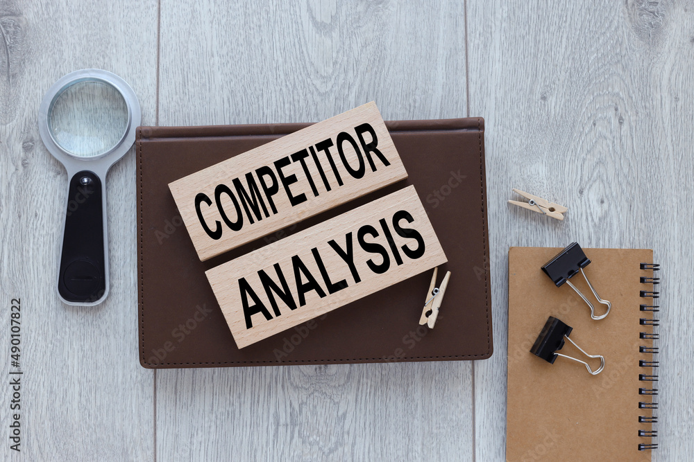 Poster wooden blocks and a notepad on a wooden background. text on blocks . competitor analysis concept