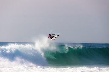 Fototapeta na wymiar Surfer athletes riding the crazy blue waves of Portugal
