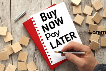 wooden background with an open notebook on the background of wooden blocks with text. BUY NOW - PAY LATER