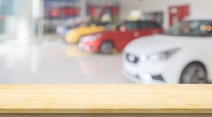 Empty wood table top with cars in showroom blurred defocused background