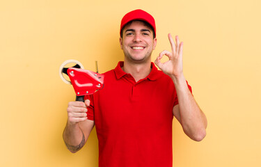 young handsome man feeling happy, showing approval with okay gesture. packer concept