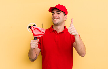 young handsome man feeling proud,smiling positively with thumbs up. packer concept