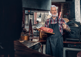 Confident old chef posing in in stylish meat grocery