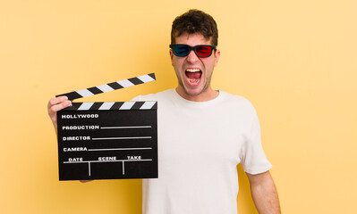 young handsome man shouting aggressively, looking very angry. cinema clapper concept