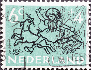 Netherlands - circa 1952: a postage stamp from the Netherlands , showing drawings on the 1952 children's stamps : Girl playing with a Dog