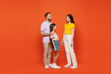 Full body side view young fun smiling happy parents mom dad with child kid daughter teen girl in basic t-shirts cuddling isolated on yellow background studio. Family day parenthood childhood concept