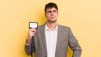 young handsome man shrugging, feeling confused and uncertain. vip pass concept