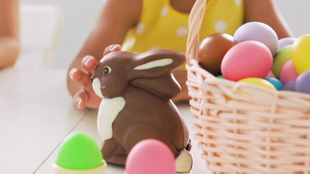 Black child strokes the Easter chocolate bunny on the back and smiles