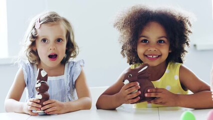 Children bit a pieces  Easter chocolate bunny  on Easter egg hunt 
