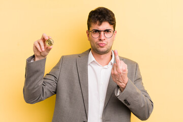 young handsome man feeling angry, annoyed, rebellious and aggressive. bitcoin concept