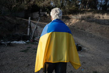 Old Ukrainian man hugs his flag looking at his land. 