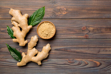 Finely dry Ginger powder in bowl with green leaves isolated on colored background. top view flat lay