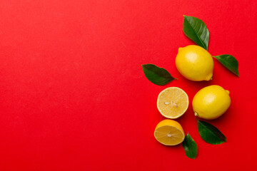 Many fresh ripe lemons with green leaves on colored background, top view, space for text