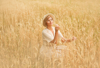 A girl in a wheat field looks at wheat grains.