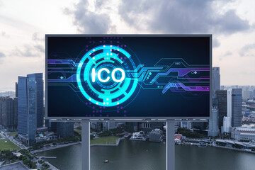 ICO hologram icon on billboard over panorama city view of Singapore at sunset. The hub of blockchain projects in Southeast Asia. The concept of initial coin offering, decentralized finance