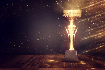 image of gold trophy over dark background, with abstract shiny lights