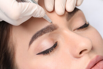 Young woman during procedure of permanent eyebrow makeup, closeup