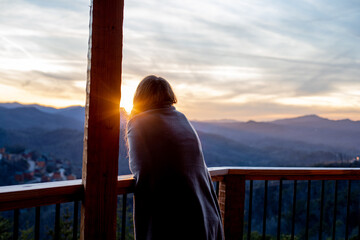 A young woman looks out over the mountains from her cabin