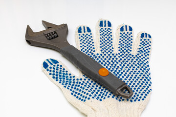 a metal adjustable wrench next to which lies a work glove