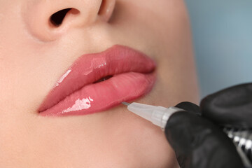 Young woman during procedure of permanent lip makeup in beauty salon, closeup