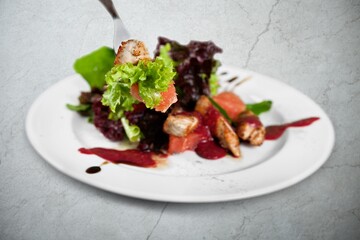 Appetizing fried meat served on a plate with vegetables on the background.