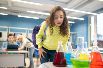 Girl leaning over laboratory flasks in classroom