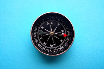 Metal magnetic compass with red arrow on blue background. Top view.