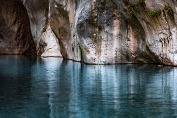 clear blue water in a deep canyon with sheer rock walls
