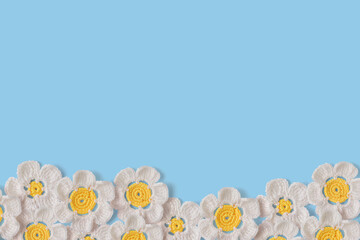 Handmade crochet and wool white daisies with copy space on blue background