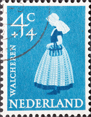 Netherlands - circa 1958: a postage stamp from the Netherlands, showing a woman in traditional...