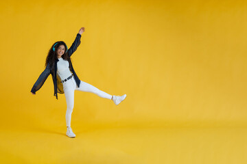 African American woman, with headphones listening to music and dancing. Yellow background