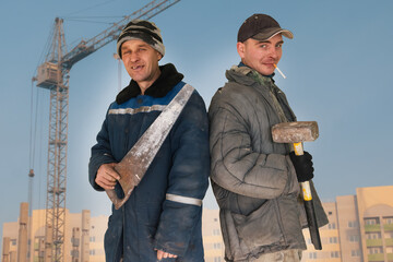 Two bad unskilled builder workers in bad dirty tattered uniform with bad tools. Concept of...