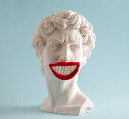 Statue of  David  head  with crazy wide smile on  blue background. Minimal art poster.