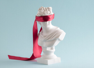 Plaster head with eyes covered red satin ribbon on blue background.