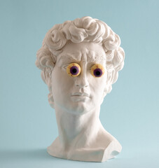 Plaster statue of David's head with bulging eyes on  blue background.