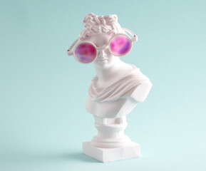 Female marble statue in large pink glasses on  blue background. Concept of  positive view  and lies. - obrazy, fototapety, plakaty
