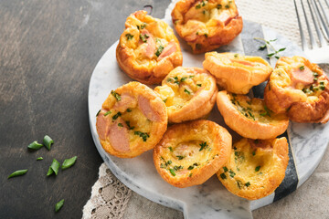 Delicious egg muffins with green onions, bacon, cheese and tomatoes on wooden board on old wooden rustic background. Healthy high protein and low carb breakfast. Homemade food.