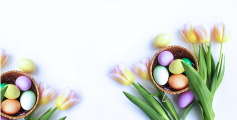 Easter flower arrangement - pink tulips, multicolored eggs in wicker baskets on a white background....