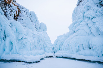 Blue ice rocks of frozen water on Lake Baikal. Grottoes and caves in winter. Beautiful giant overhanging ice background.