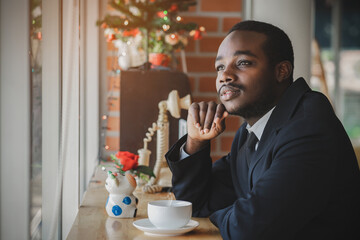 African businessman thinking and looking out the window worried about business in coffee shop