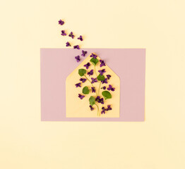 Creative layout with envelope with violets flowers and leaves. Spring flowers concept. Greeting card concept. Flat lay, top view.